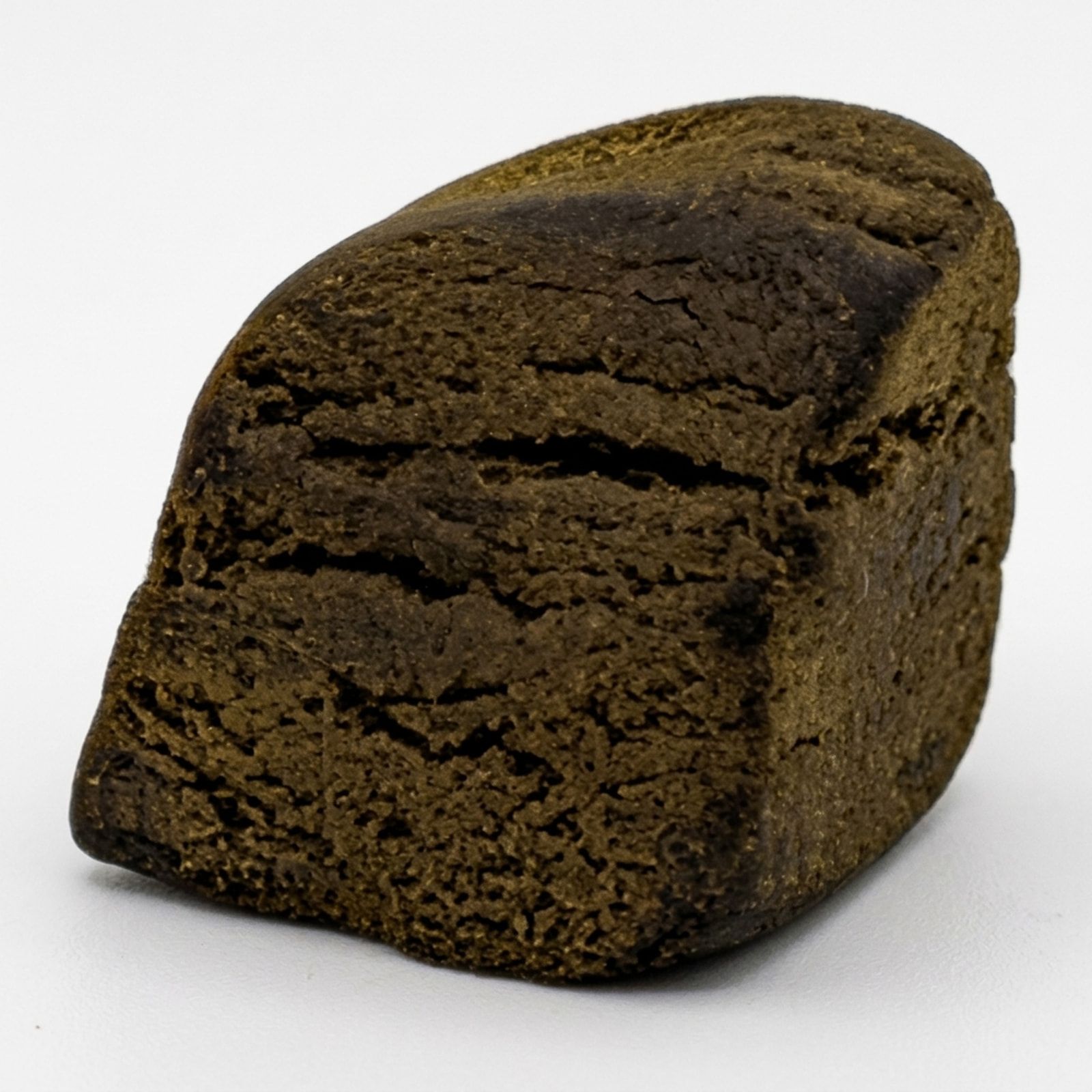 A wedge of golden-brown blonde hash photographed on a white background, its layered, pressed texture visible.