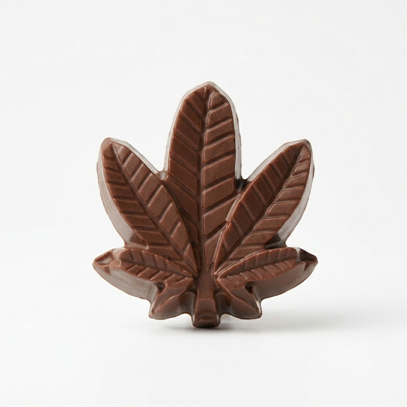 A single milk chocolate moulded in the shape of a cannabis leaf, photographed on a white background.