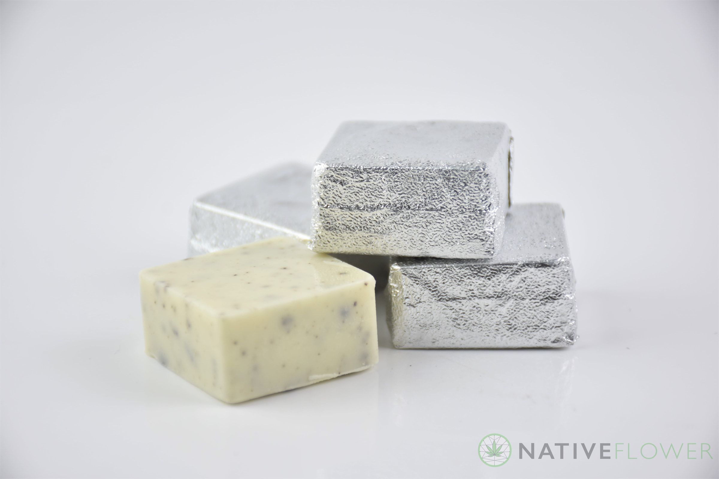 An unwrapped cookies-and-cream white chocolate square in front of three foil-wrapped squares.