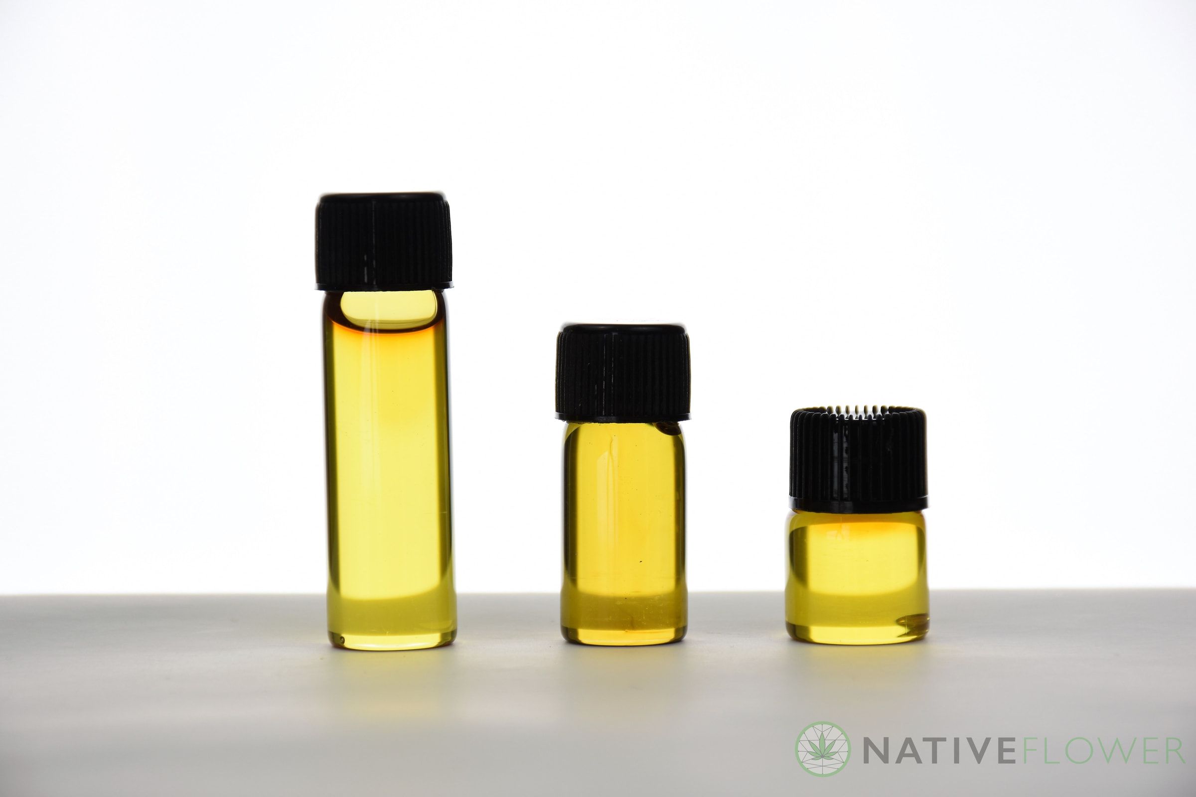 Three glass vials of golden distillate lined up in descending sizes.