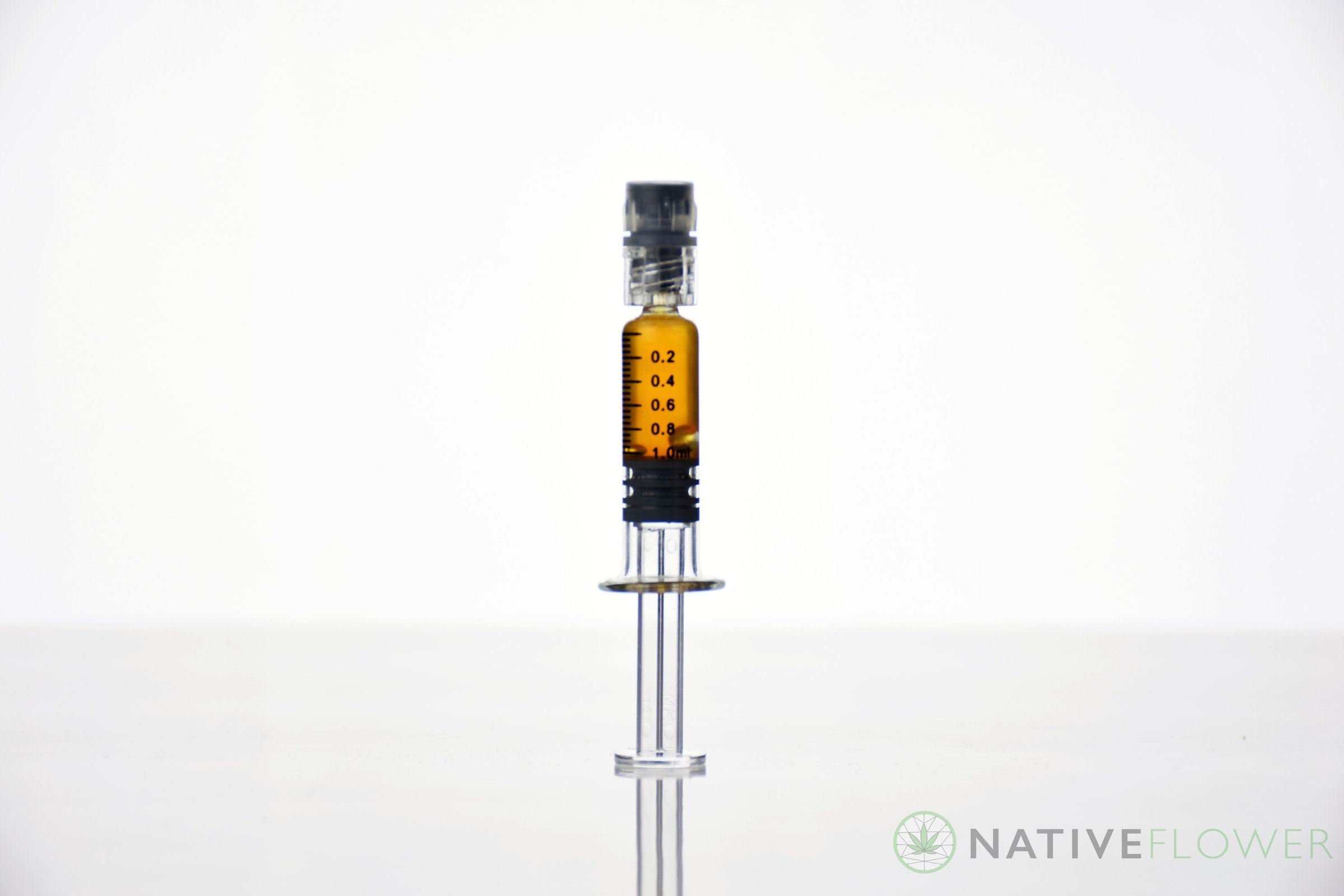 A graduated glass applicator of amber distillate standing upright.