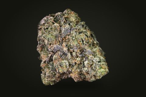 Godfather OG from a third side: a tall, dense bud with purple-tinged leaves and orange hairs, on a plain black background.