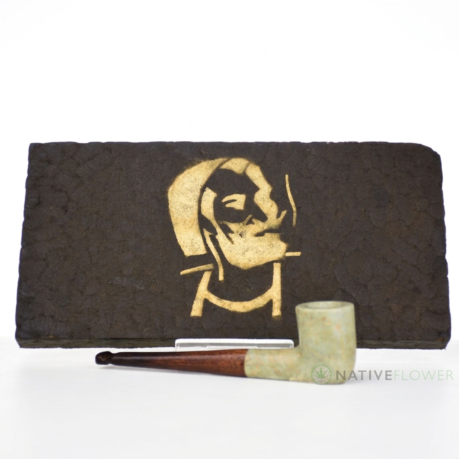A large dark hash slab stamped with a gold stencil, a stone pipe resting in front, on a white background.