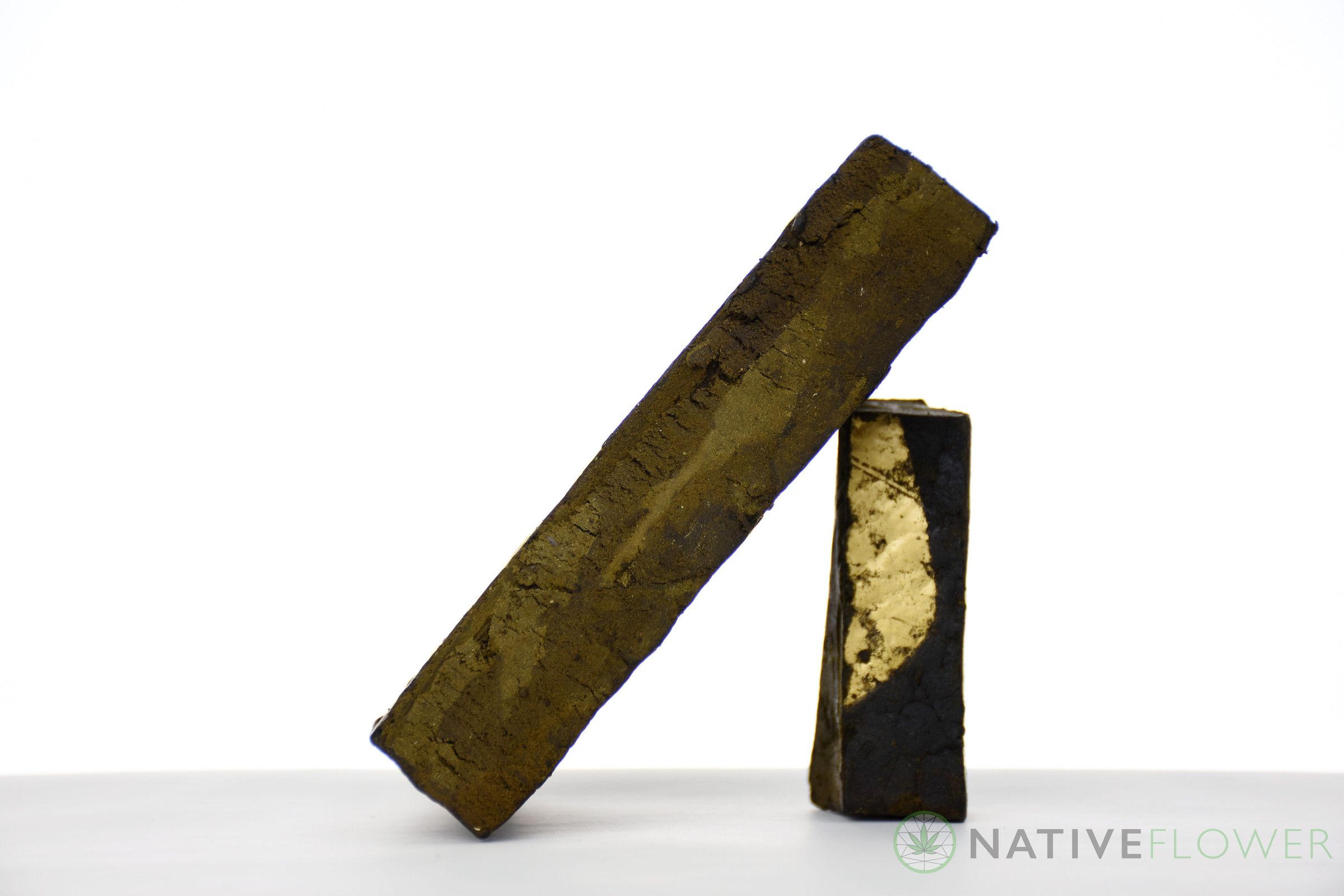 Two pressed hash bars, one leaning against the other to show a pale cut face.