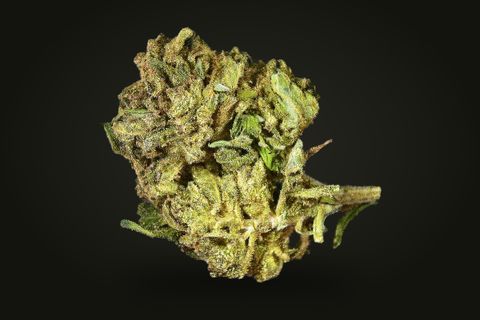A cured bud of Hindu Kush, yellow-green with frosted sugar leaves standing out from it and a stem at its right, on a plain black background.