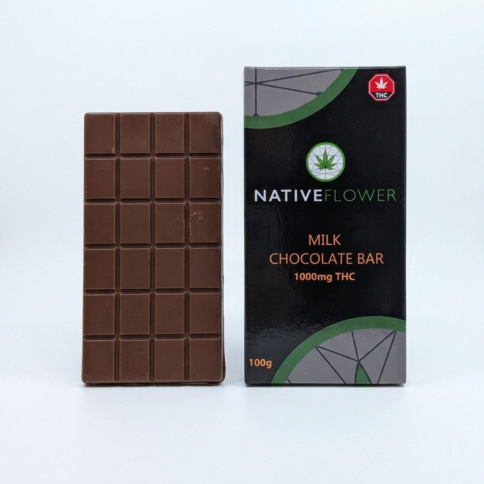 An unwrapped milk chocolate bar standing beside its black Native Flower retail box on a white background.