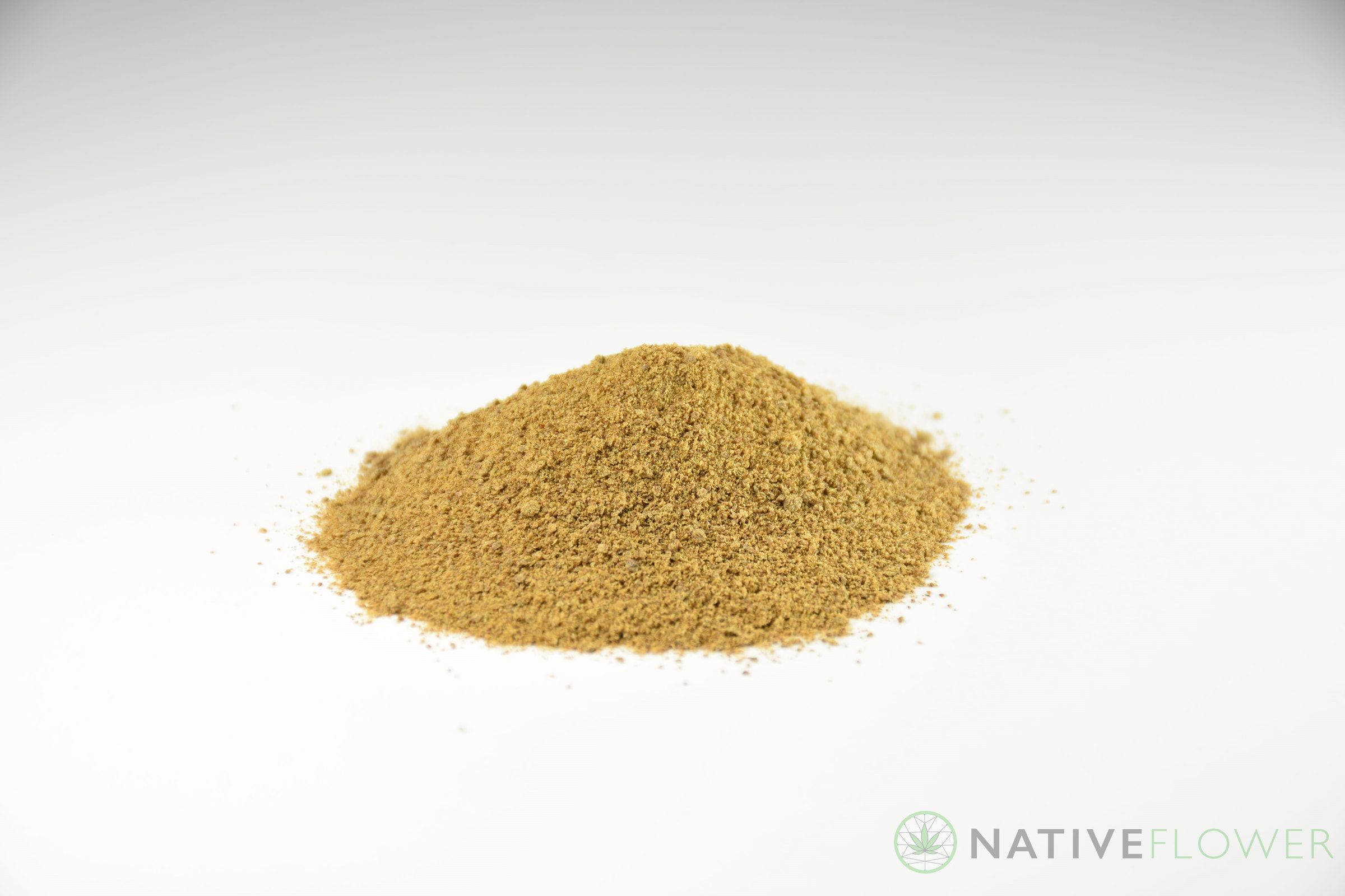 A cone-shaped pile of pale gold kief on a white surface.