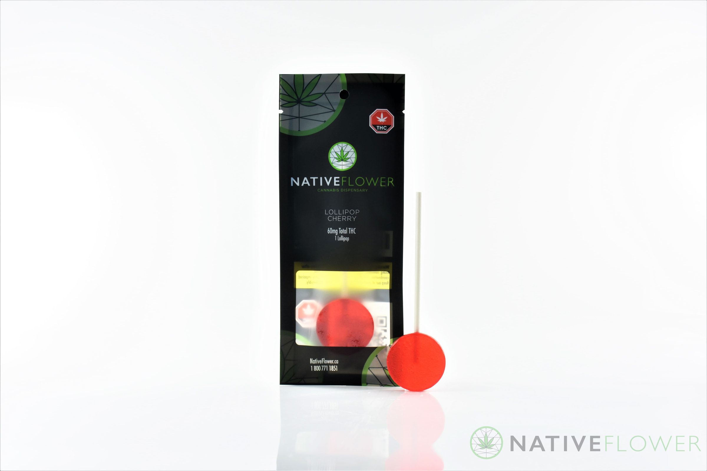 A red lollipop standing beside its pouch.