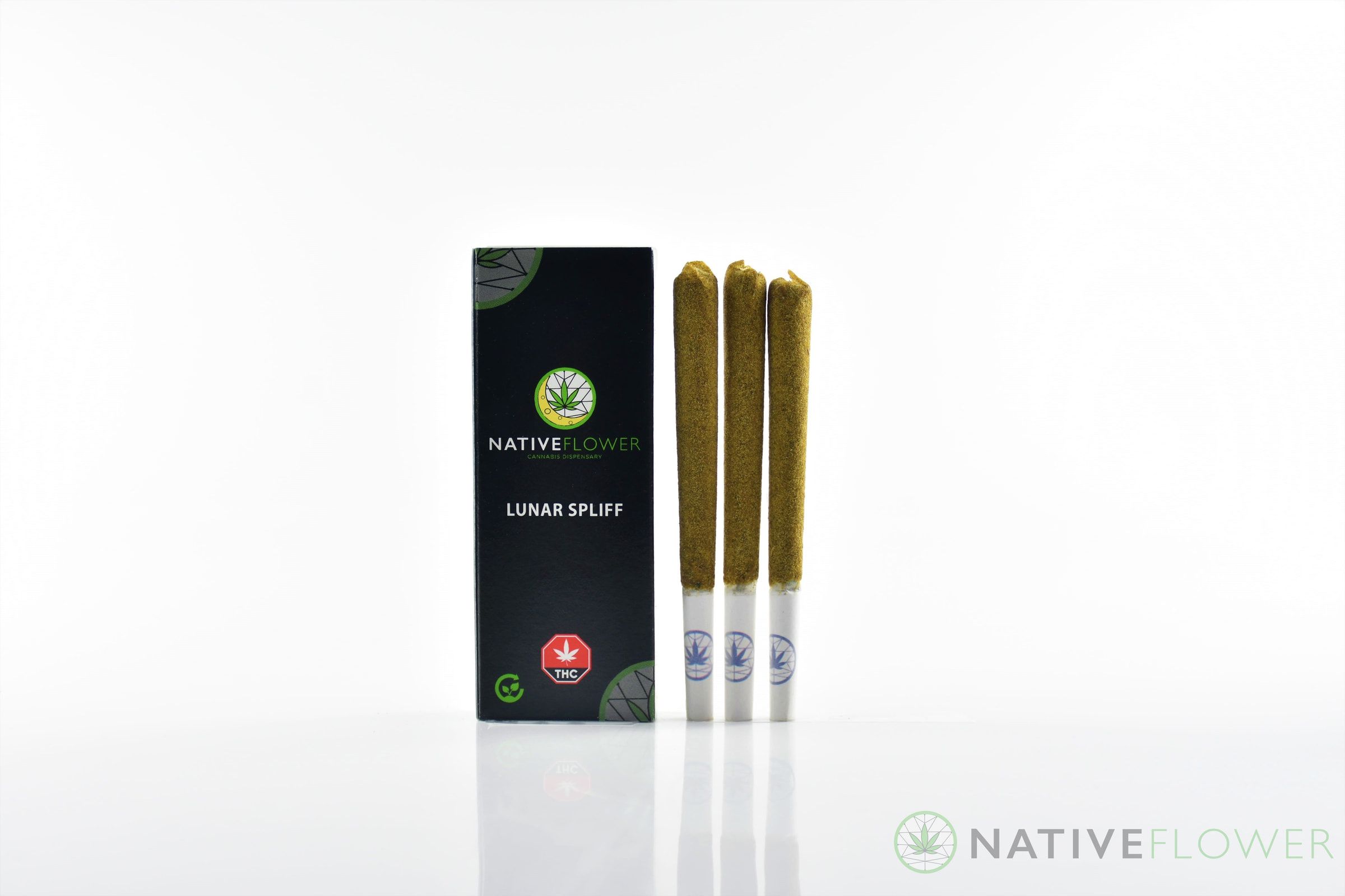 Three kief-coated spliffs standing beside their black carton.