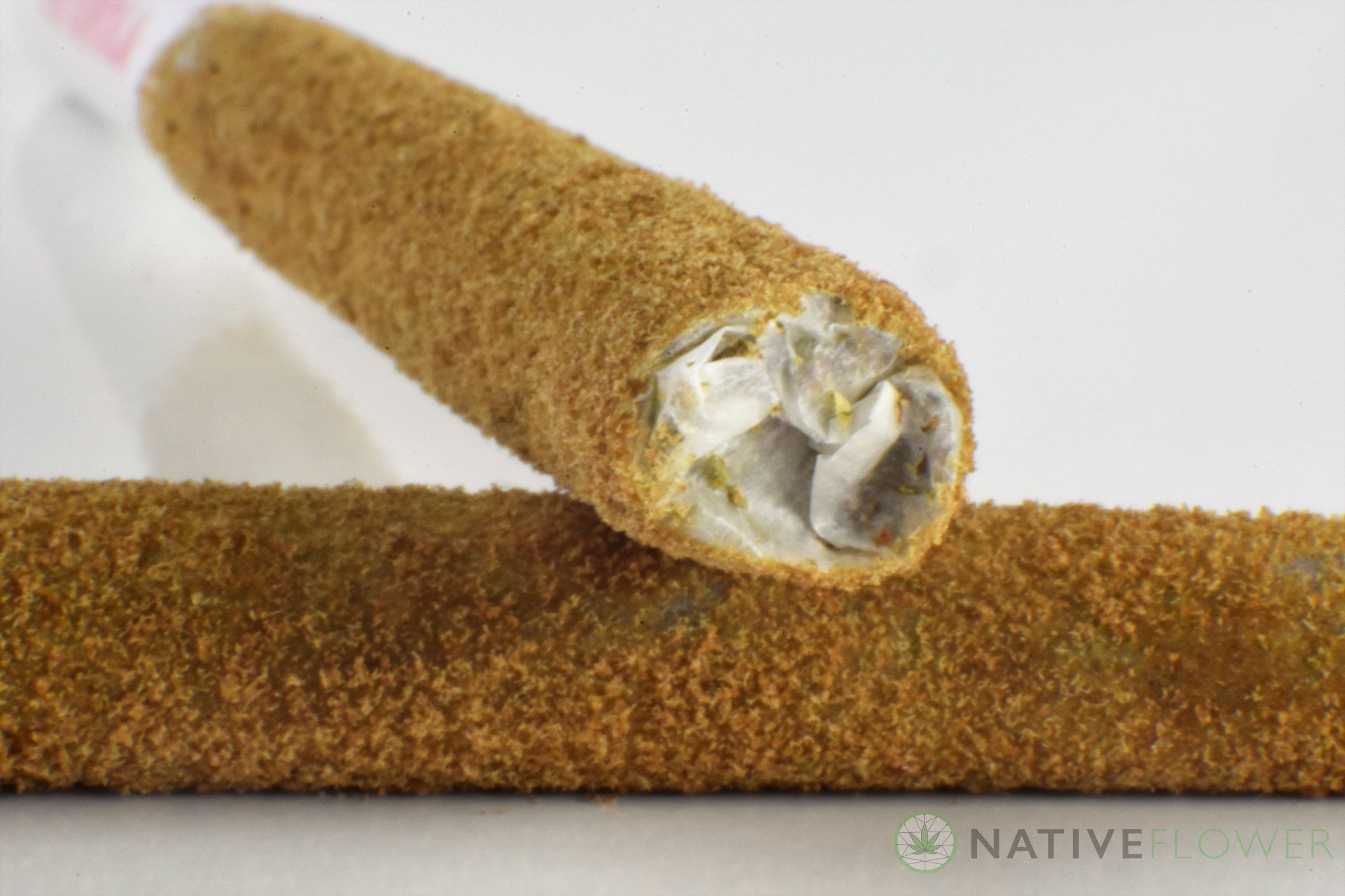 A close-up of two kief-coated Lunar Spliffs, one showing its rolled tip.