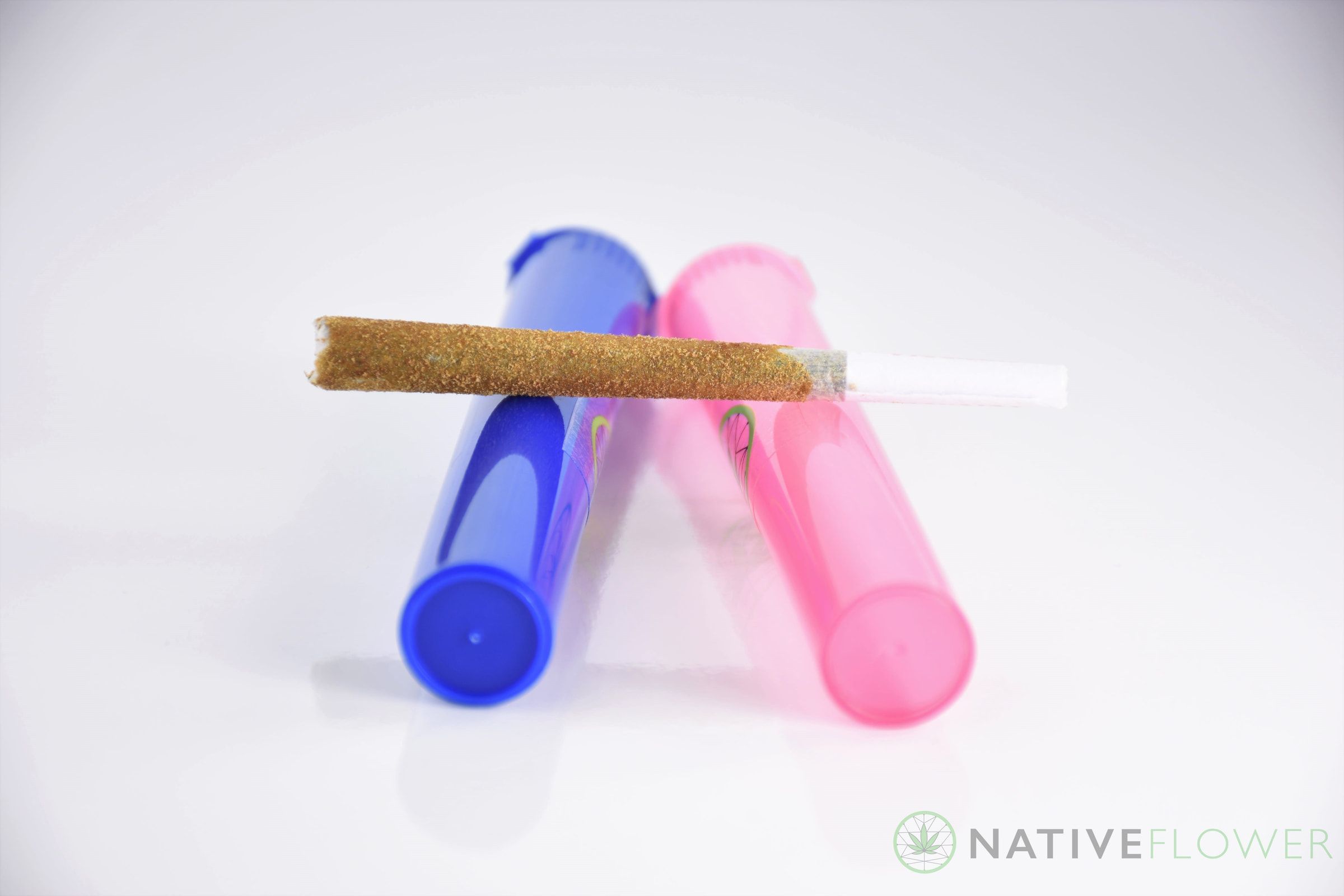 A kief-coated Lunar Spliff resting across blue and pink storage tubes.
