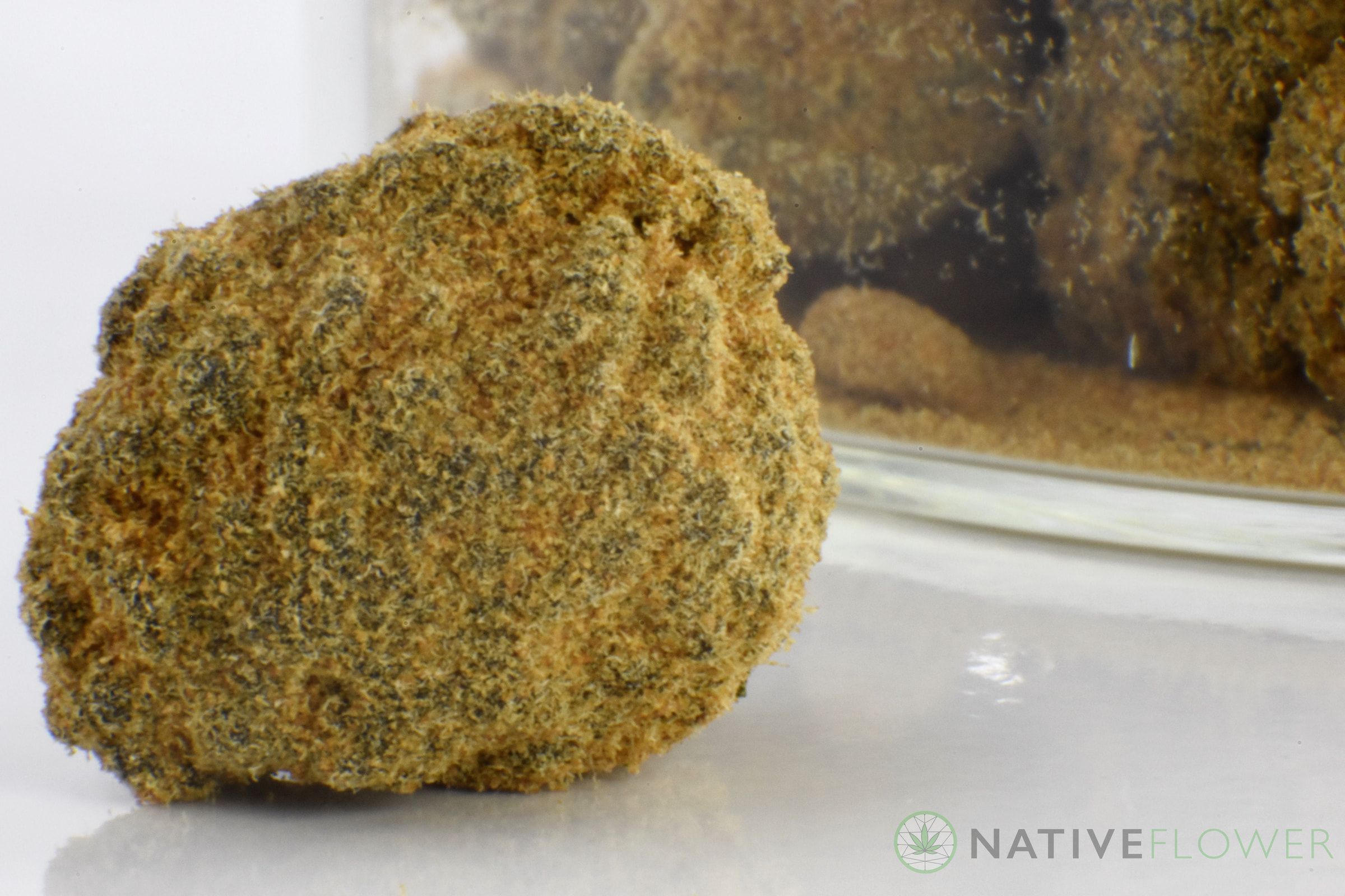 A single kief-coated moon rock in close-up, a jar of more behind it.