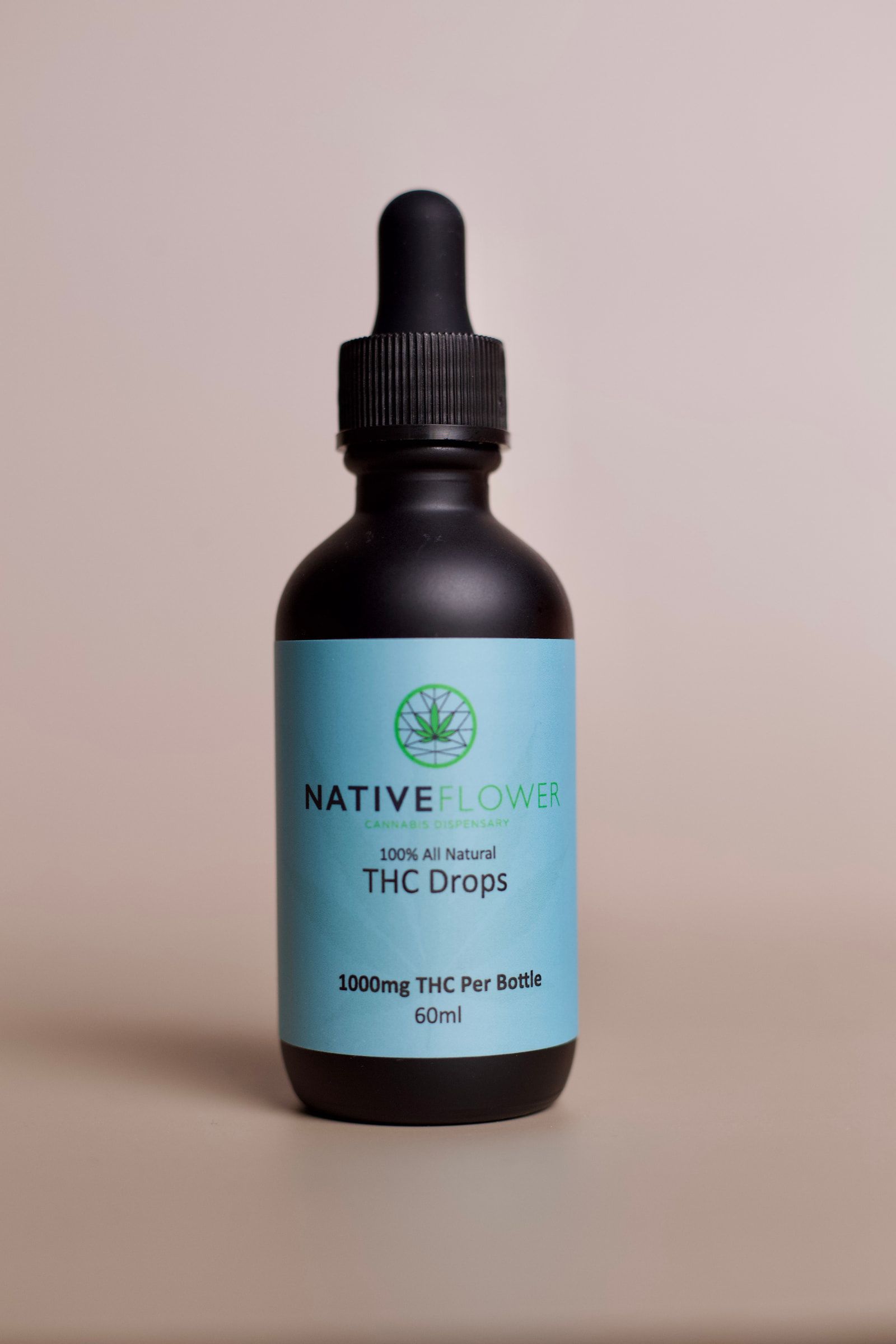 A blue-labelled bottle of Native Flower THC drops, label facing forward.