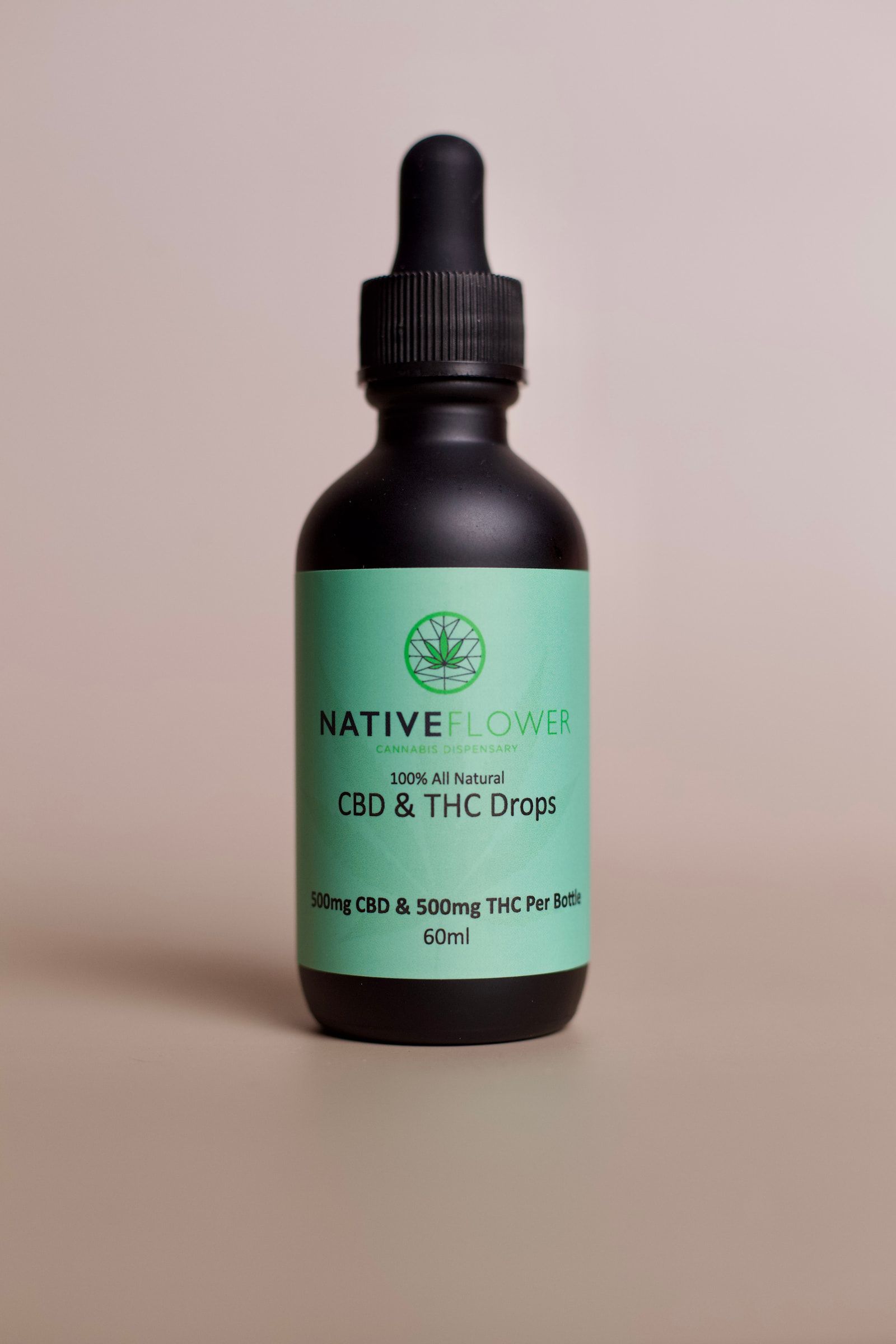 A black dropper bottle of Native Flower CBD and THC drops with a green label.