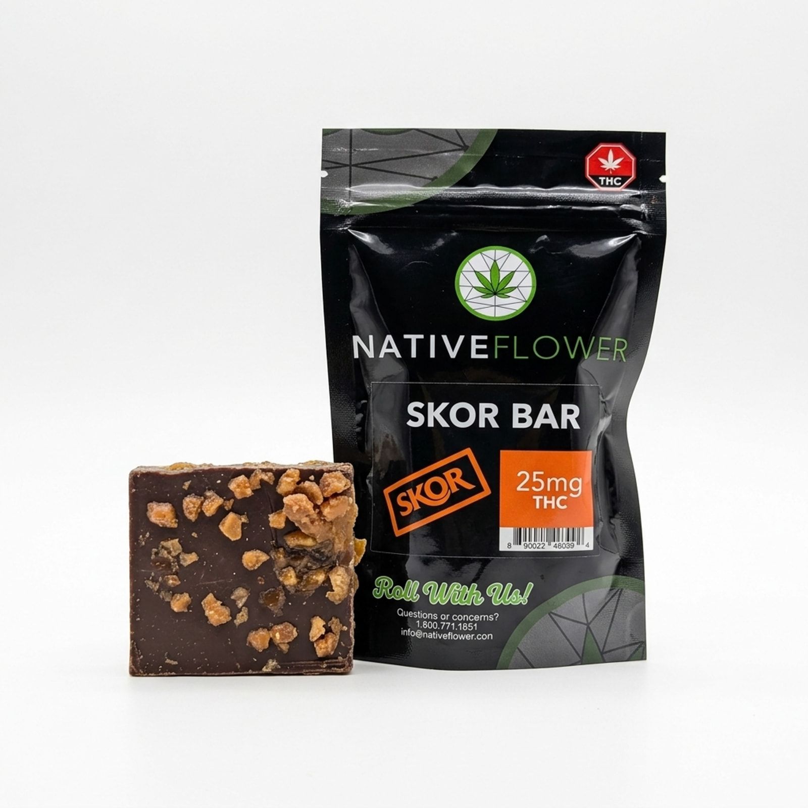 A toffee-topped chocolate square standing beside its black Native Flower Skor bar pouch on a white background.