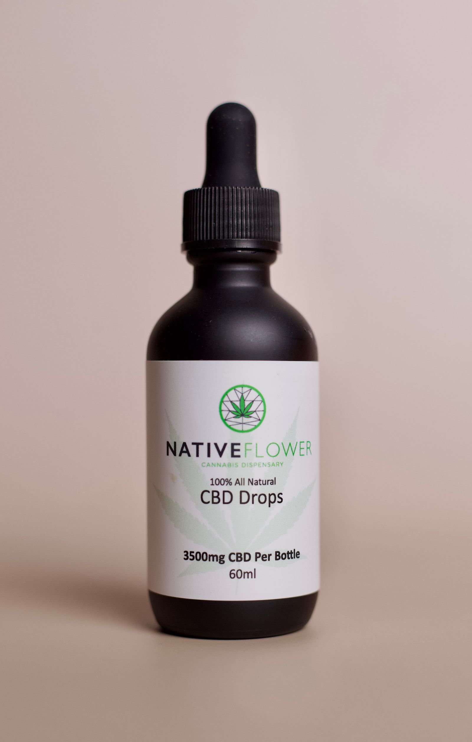A tall bottle of Native Flower CBD drops with the dropper cap seated.