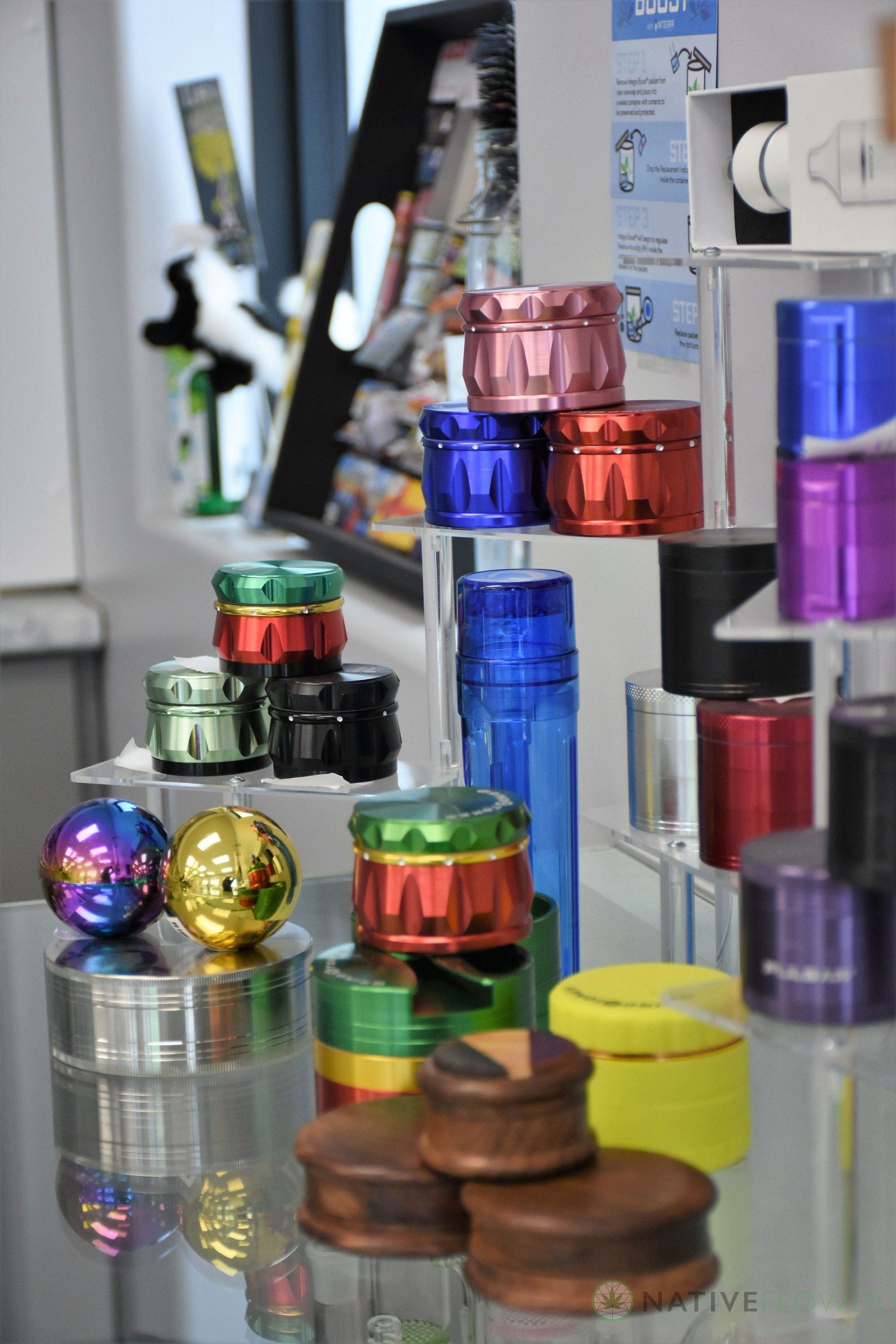 A counter display of metal grinders in red, blue, purple and gold, arranged by size.