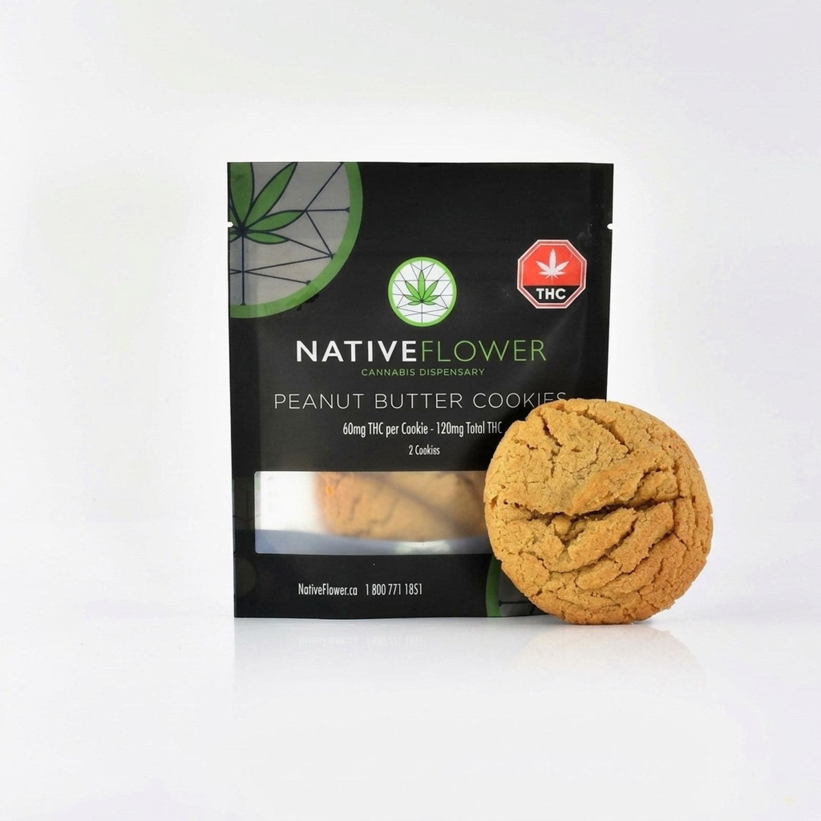 A Native Flower peanut butter cookie leaning against its black pouch, on a white background.