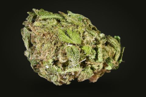 A cured bud of Thai, light green with frosted sugar leaves folded over it and tan hairs, on a plain black background.