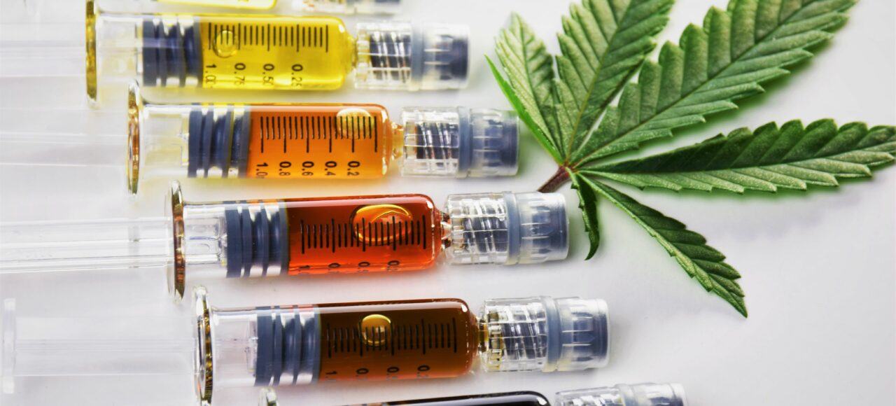 Different cannabis oils in syringes with a cannabis leaf.
